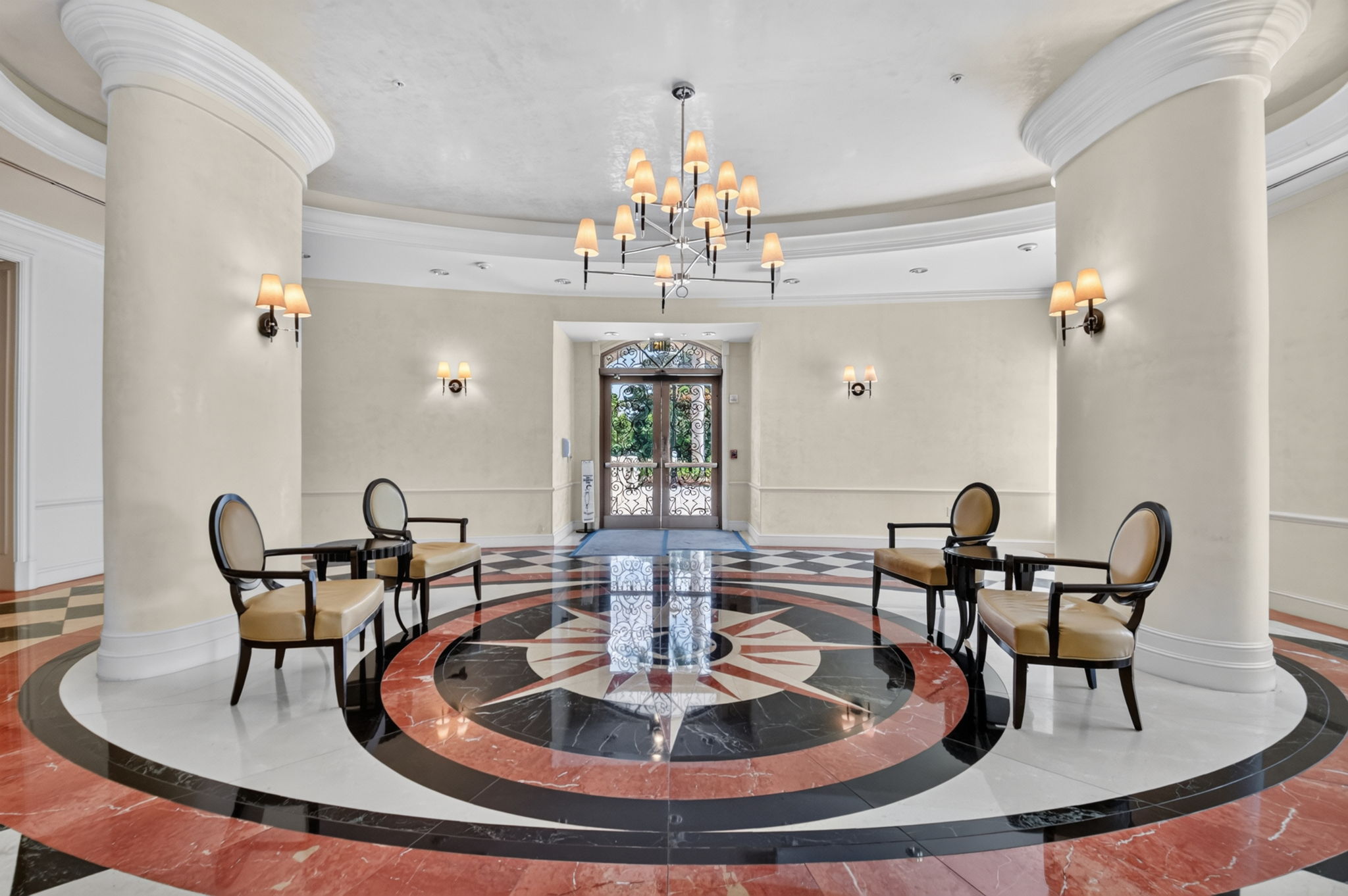 The rotunda lobby at The Metropolitan in Downtown West Palm Beach, with a chandelier, columns and an inlaid marble compass floor