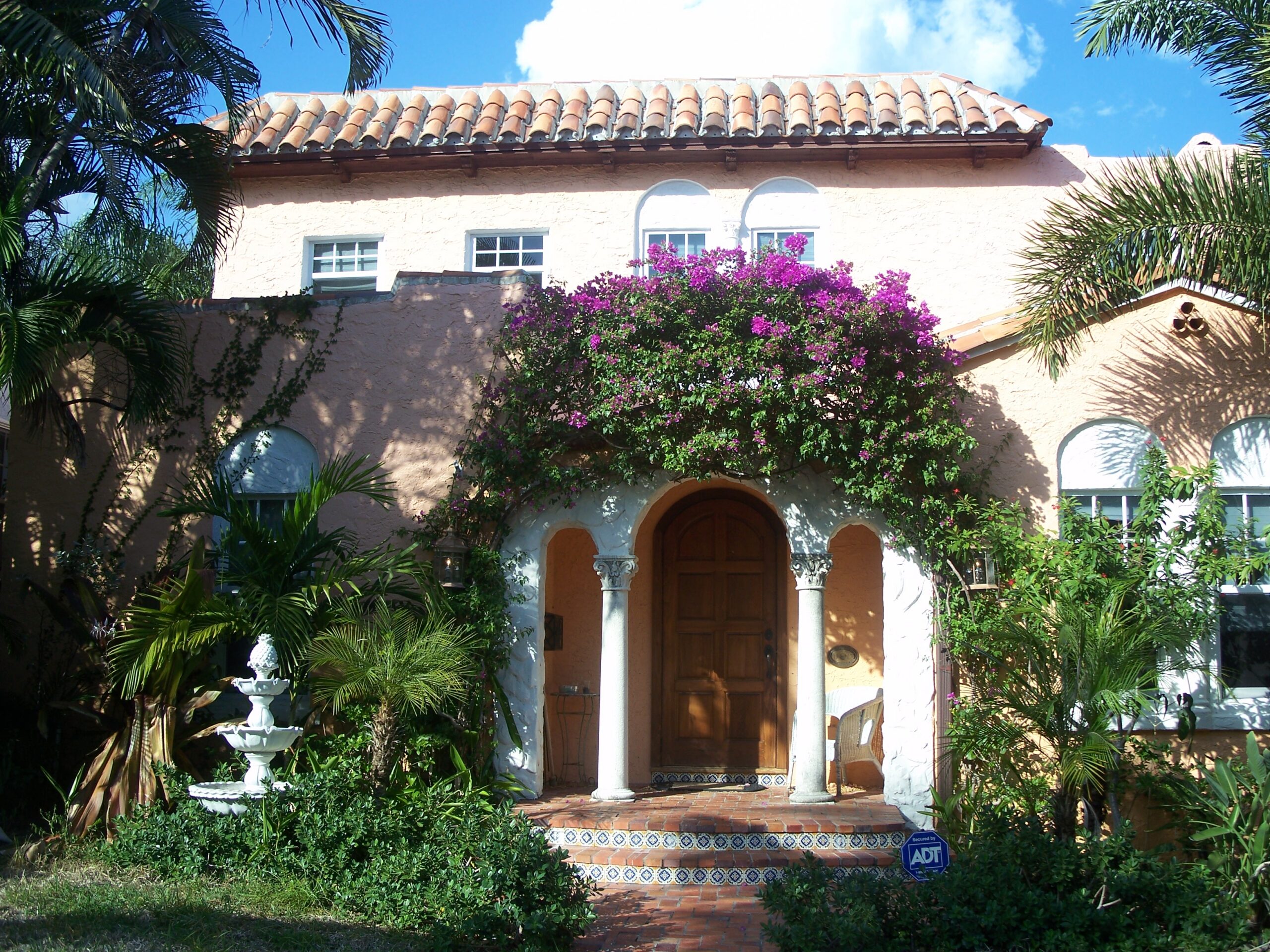 Pink Mediterranean Revival home with a terra cotta tile roof, arched entry and bougainvillea in the Flamingo Park Historic Residential District, West Palm Beach
