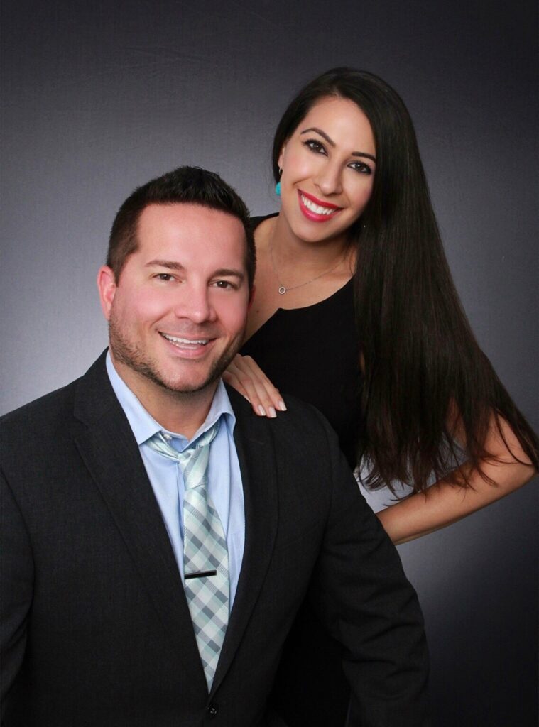 Justin and Alyse Keller of The Keller Team at Compass posed together in a studio portrait, Justin in a dark suit and Alyse in a black top